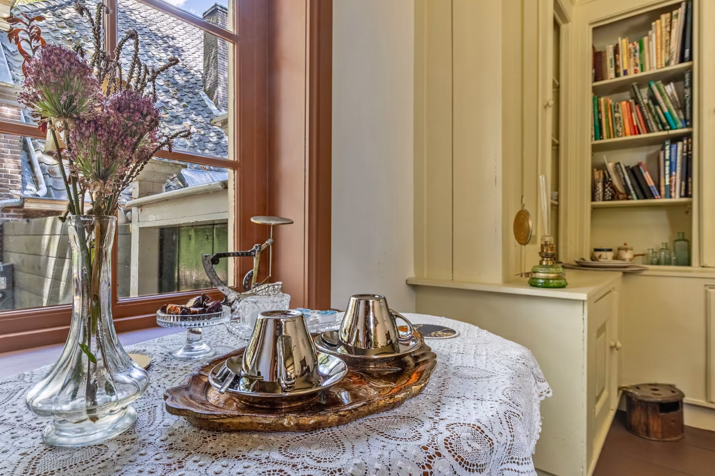 Ontbijttafel met zilveren thee- en koffieservies aan het raam