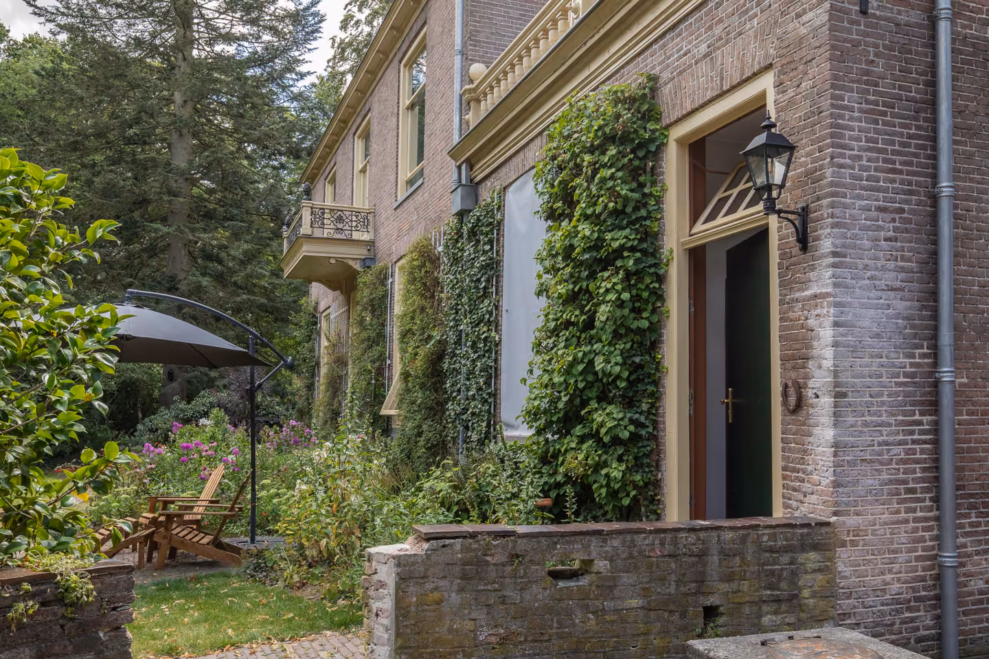 Achtergevel van Huis Overcingel met klimop en het terras aan de tuin