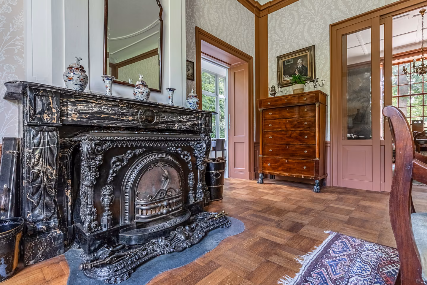 Rijk bewerkte gietijzeren schouw in de salon van Huis Overcingel