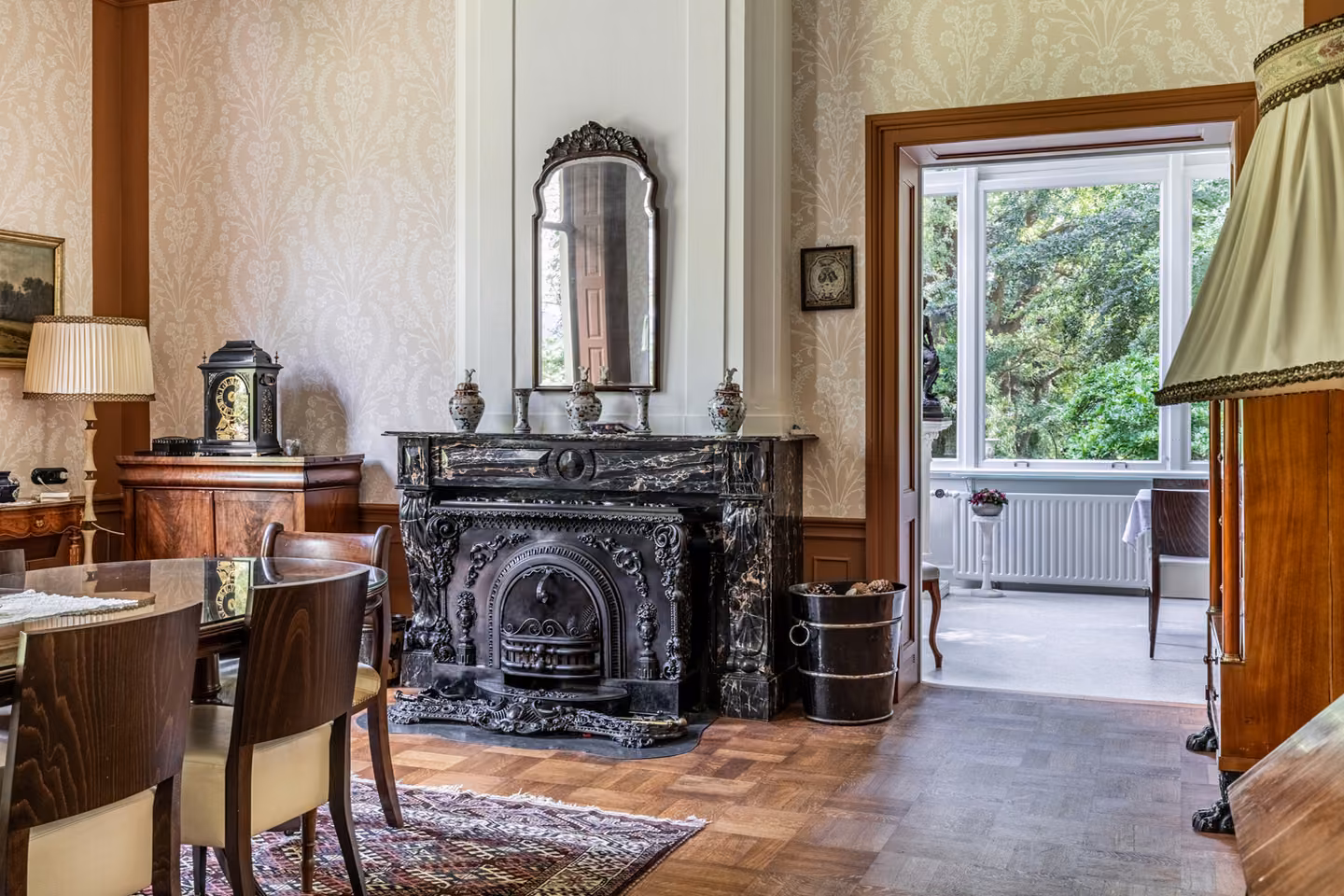 Salon met zwarte marmeren schouw en raam naar de tuin