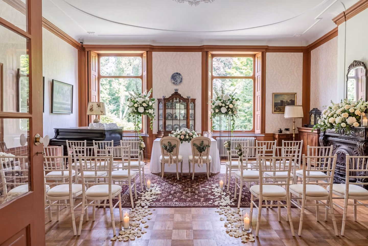 Doorkijk door de openstaande deur naar de salon, ingericht voor een trouwceremonie