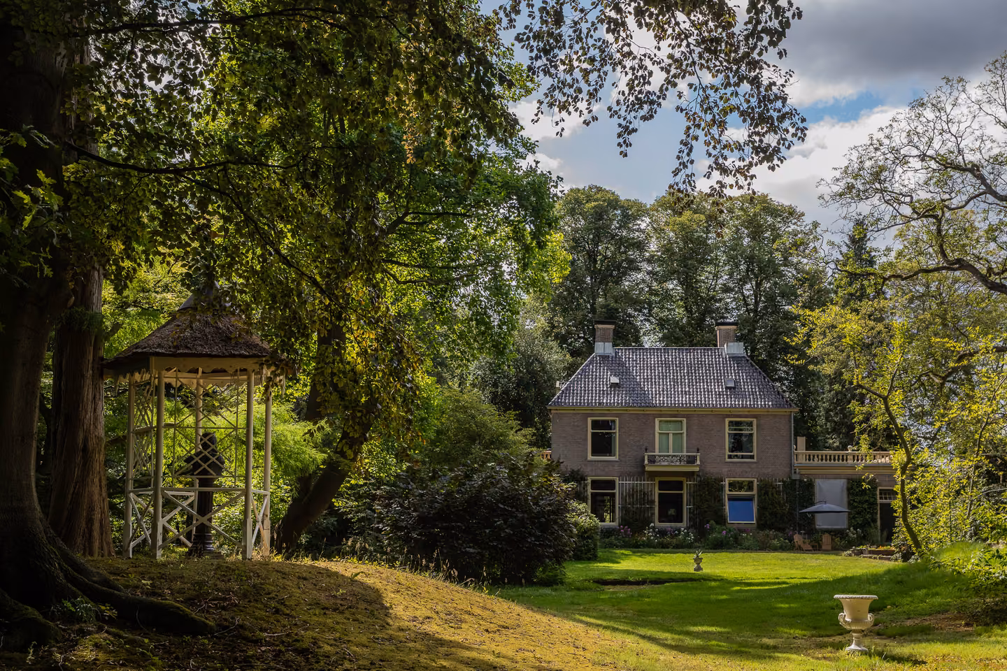 Het gazon met het witte prieel en Huis Overcingel op de achtergrond